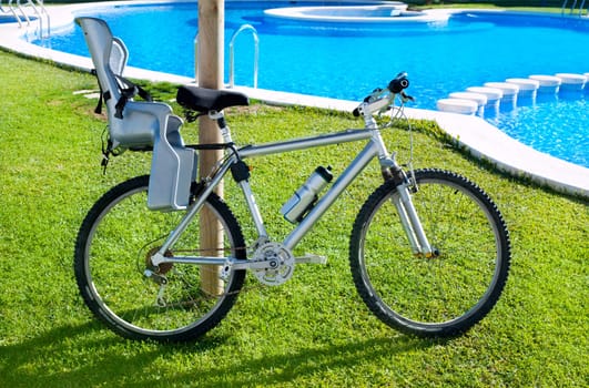 bicycle with baby seat in grass pool outdoor on summer vacation