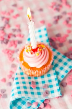 Close-up of a pink muffin with party candle. Studio shot.