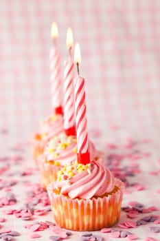 Close-up of pink muffins with party candles. Studio shot.