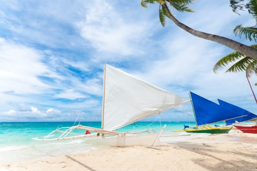 traditional paraw sailing boats on white beach on boracay island, Philippines