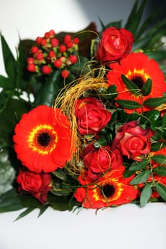 Colourful wedding corsage of orangey-red flowers in green foliage