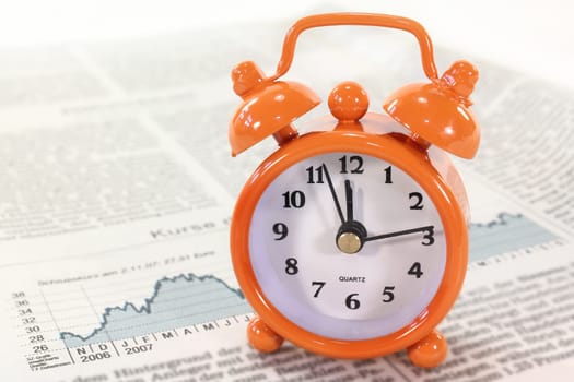 an alarm clock on a stock market sheet