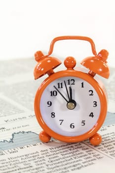 an alarm clock on a stock market sheet
