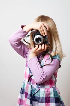 Little girl with a vintage camera. Studio shot.
