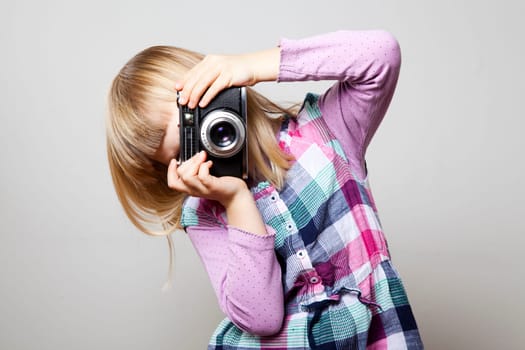 Little girl with a vintage camera. Studio shot.