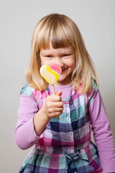 Cute little girl with a heart shape lollipop. Studio shot.