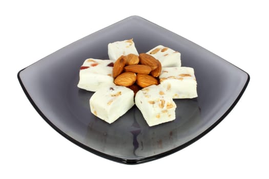 Delicious nougat on black glass plate, isolated on white