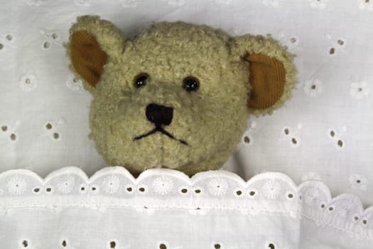 Tired teddy bear in bed