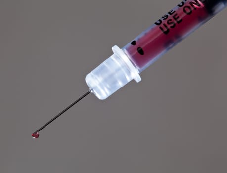 Macro of a drop of blood on the end of a hypodermic syringe needle
