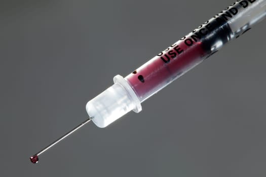 Macro of a drop of blood on the end of a hypodermic syringe needle