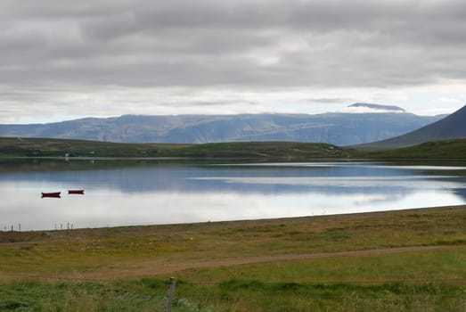 River with boats between mountains of Akureyri in Iceland