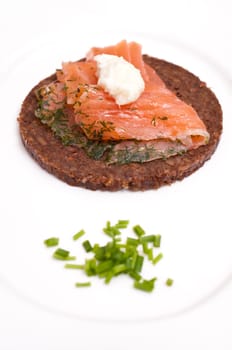 A plate with a canape of wholemeal pumpernickel with graved salmon and creamed horseradish and chives