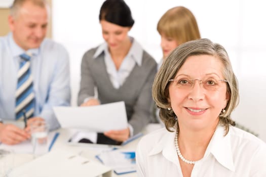 Business team meeting executive senior businesswoman with colleagues in background