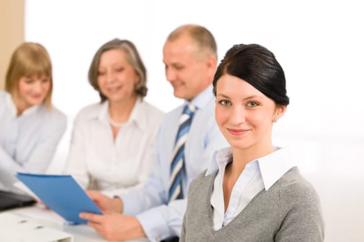 Young executive woman looking camera during meeting with team colleagues