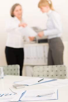 Office supply on table - two business women out of focus