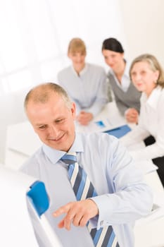 Giving presentation executive businessman pointing at flip chart team looking