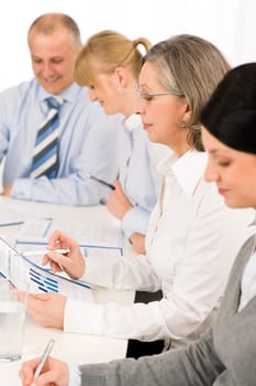 Business meeting team examining sales report sitting around table