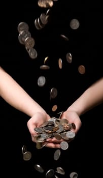 Raining coins in hands towards black background