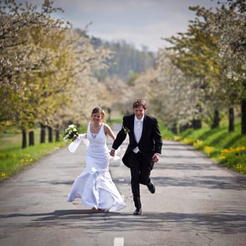 young wedding couple - freshly wed groom and bride posing outdoors on their wedding day