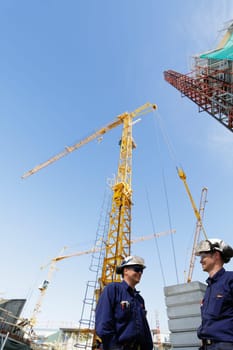 construction-workers with large cranes and scaffolding in background