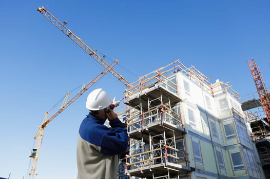 construction-worker with building-site in background, cranes and scaffolding