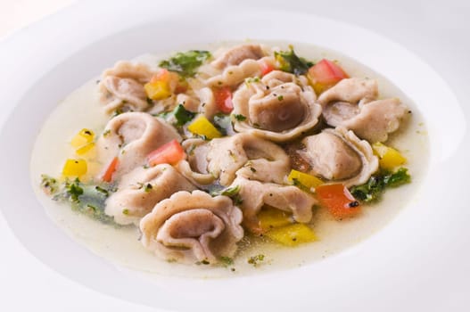 Fresh capeletti soup with vegetables close up