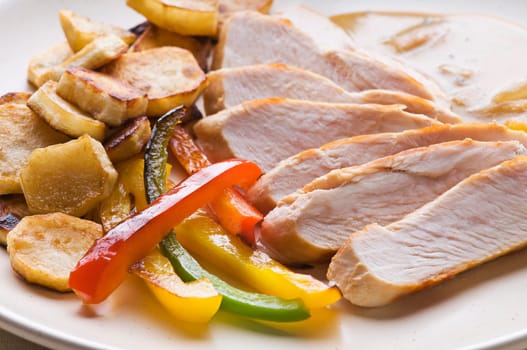Fresh sliced chicken with roasted potato and pepper close up
