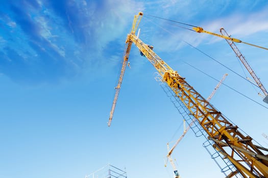 large construction-cranes with blue sky and clouds