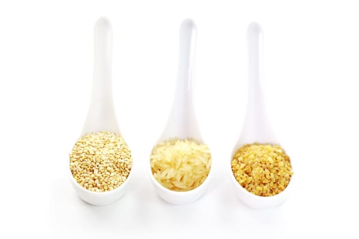 Three cereal seeds in spoon on white background