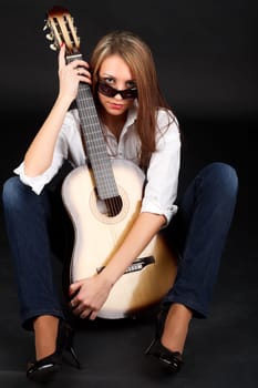 Portrait of a young attractive woman with a guitar on a black background