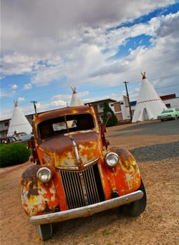 Old abandoned rusty car with blue sky and clouds above