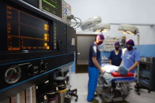 Team work with doctors, nurses, surgeons performing surgery on sick patient in hospital operation room. Focus on foreground