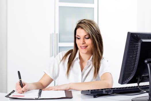 beautiful young business woman writting in office