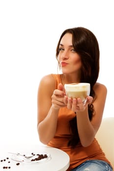 Young mischievous woman with a cup of cappuccino coffee against white background