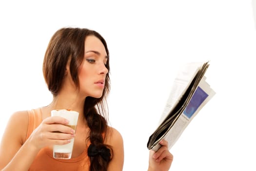 Young woman with a glass of latte macchiato coffee reading newspaper against white background