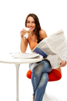 Happy young woman holding a newspaper and a glass of latte macchiato coffee against a white background