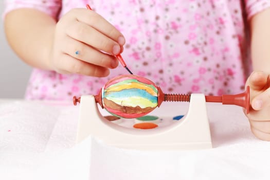 Cute little girl painting Easter eggs