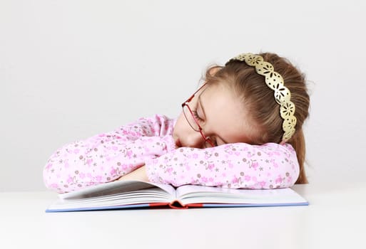 Tired schoolgirl sleeping on book instead of learning