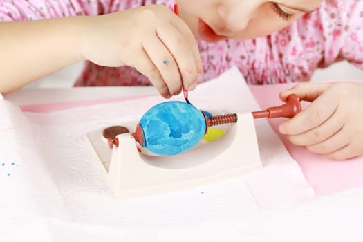 Cute little girl painting Easter eggs
