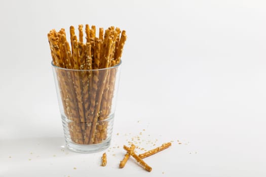Pretzel sticks in a glass,many crumbs on the outside,photographed from the front