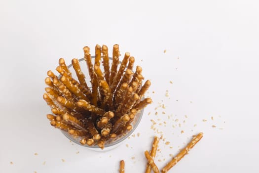 Pretzel sticks in a glass,many crumbs around the outside,photographed from above
