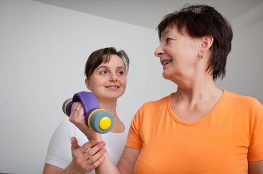 Senior woman exercising with trainer