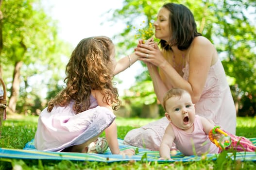 Mother with children having happy time - smelling flowers