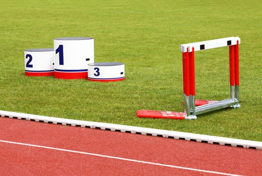 Track lanes with winner&#039 s podium and hurdles on green grass