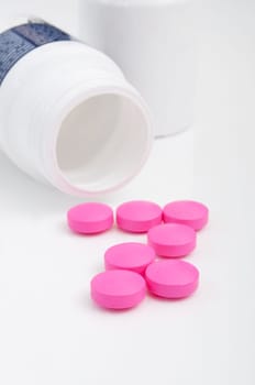 Pink Pills in White Bottle On White Background