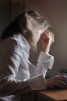 Young unhappy business woman working overtime at computer, night setting, motion blurr