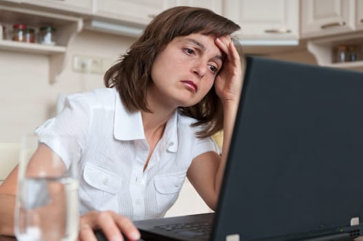 Young business woman in depression working on laptop at home - portrait