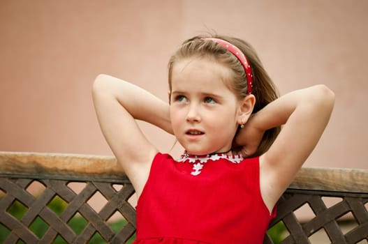 Portrait of small girl putting necklace on neck looking away