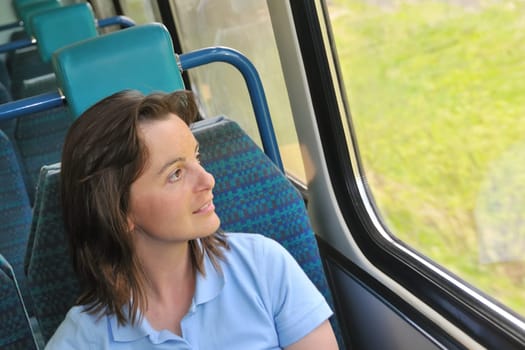 Young woman passanger sitting inside train and looking trough window