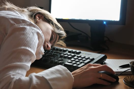 Deatil portrait of young business woman sleeping on keyboard - night setting, monitor in background